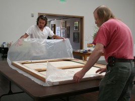 Intern Colin helps PAAM Archivist James Zimmerman wrap a painting in plastic for safe transportation