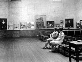 archival image of two women sitting on a bench in the museum looking at an exhibition